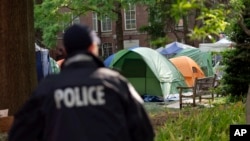Un agente de la policía de la Universidad George Washington supervisa la zona en la que los estudiantes mantienen una protesta pro-Palestina por la guerra entre Israel y Hamás, el 26 de abril de 2024, en Washington. 