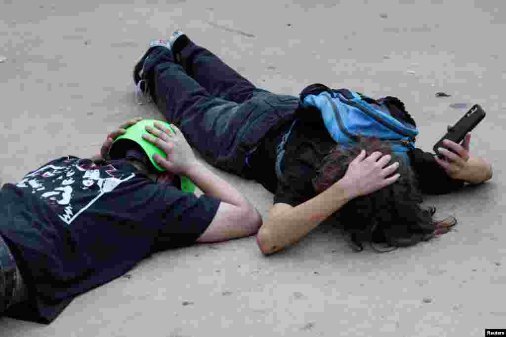 People take cover as sirens sound in central Israel in response to what Israel's military says projectiles fired from Lebanon, in Tel Aviv.