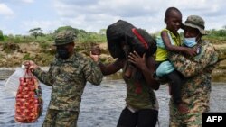 Miembros del Servicio Nacional de Fronteras de Panamá ayudan a los migrantes a cruzar el río Chucunaque después de que caminaron durante cinco días en el Darién Gap, en la aldea Bajo Chiquito, provincia de Darién, Panamá, el 10 de febrero de 2021.