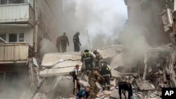 Empleados del servicio de emergencia ruso trabajan en un bloque de apartamentos que se derrumbó parcialmente después de un ataque con misiles de Ucrania en la ciudad rusa de Belgorod, Rusia, el 12 de mayo de 2024.