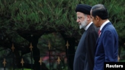 Iranian President Ebrahim Raisi and Indonesian President Joko Widodo walk upon their meeting at the Presidential Palace in Bogor, Indonesia, May 23, 2023. 