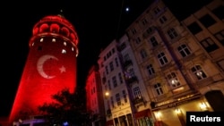 Sebuah bendera Turki diproyeksikan ke Menara Bersejarah Galata di Istanbul (12/12) untuk menghormati para korban ledakan di stadion sepakbola kota itu, Sabtu (10/12). 
