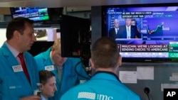 Traders at the New York Stock Exchange listen to President Donald Trump's televised White House news conference, March 17, 2020. Stocks posted gains on Wall Street after Trump and his team announced more measures to combat the coronavirus outbreak. 